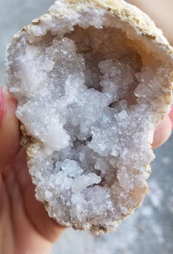 close-up of reviewer holding a geode that's been cracked open with crystals inside