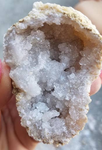 close-up of reviewer holding a geode that's been cracked open with crystals inside