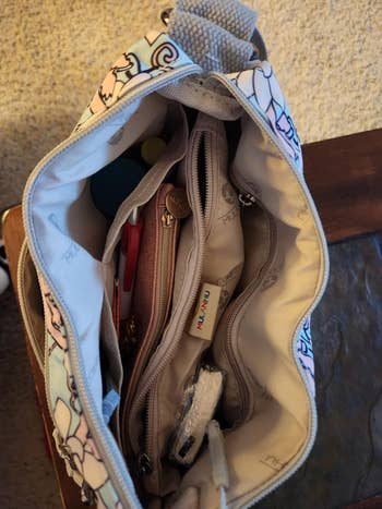 Open handbag with compartments, containing various items like a pen, coin pouch, and small accessories
