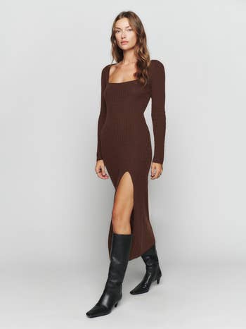a model wearing a brown cable knit sweater dress with a leg slit and black knee-high boots