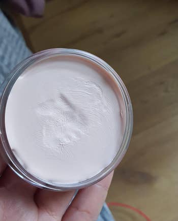 a reviewer holding a small tub of the primer 
