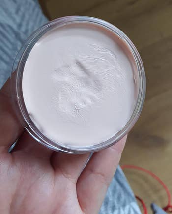 a reviewer holding a small tub of the primer 