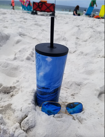 Reviewer propping a blue version of it on the beach in the sand 