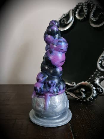 Purple, black and gray boiling cauldron dildo in front of mirror
