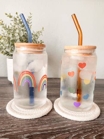 Two decorated glass mason jars with a rainbow print and a rainbow heart print 