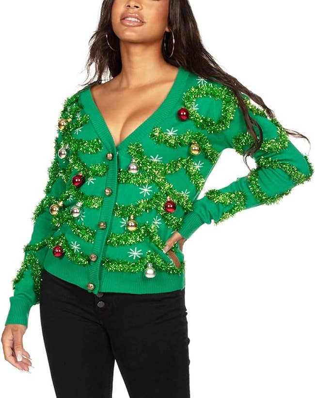 model in green cardigan sweater with sparkly green tinsel and ornaments on it
