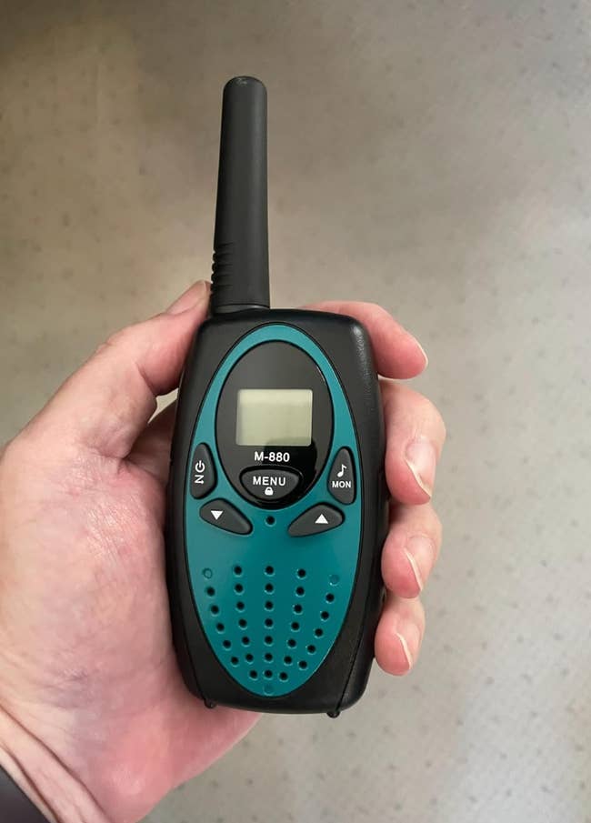 Hand holding a black and blue walkie-talkie, model M-880