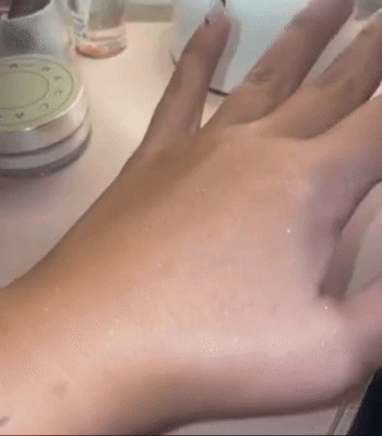 A reviewer with a sparkly hand showing how the glitter reflects in the light 
