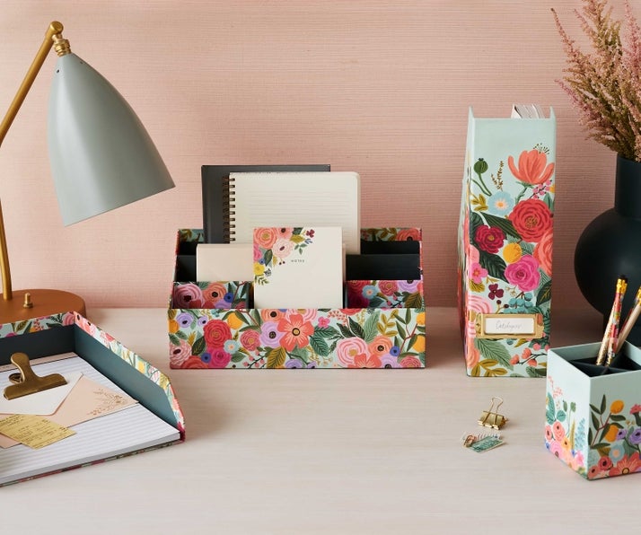 the organizer with three small front compartments and two larger compartments on a desk holding notepads