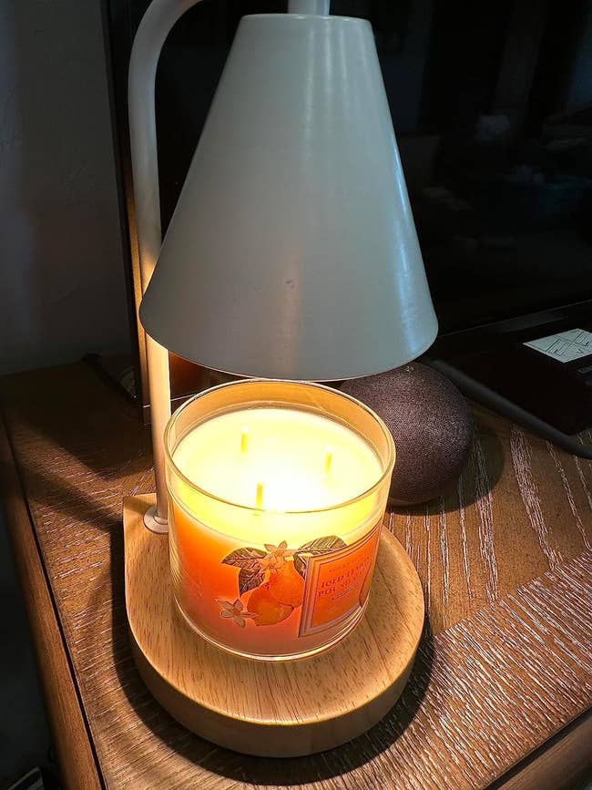reviewer's white lamp with a wooden base warming a melting candle 