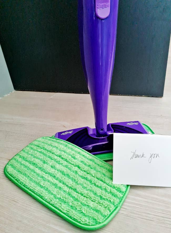 reviewers reusable pad next to a note and their Swiffer