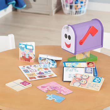 Purple mailbox toy with face on it and pieces of play mail