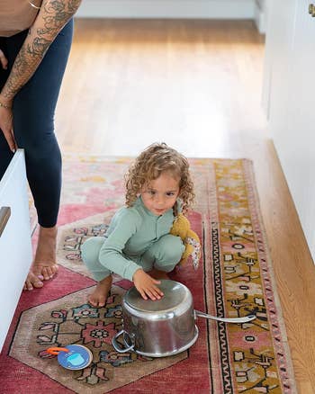 child next to pot with card showing saucepan