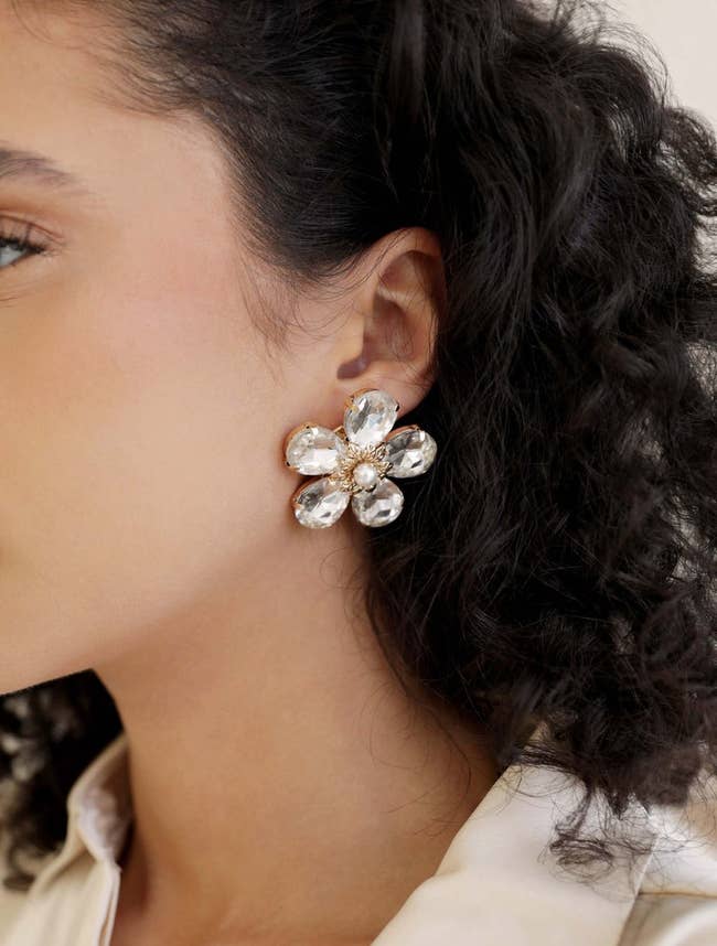 model wearing large clear crystal flower stud earring with faux pearl center