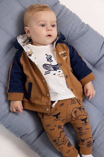 a baby model in an orange jacket with blue accents