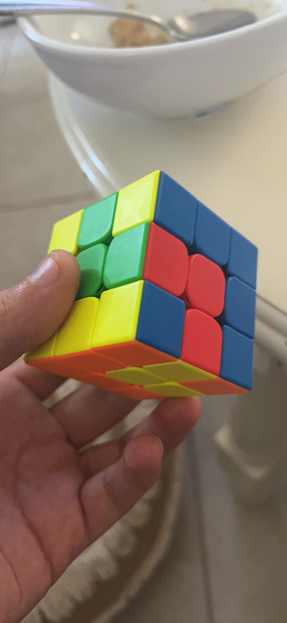 Hand holding a solved Rubik's Cube
