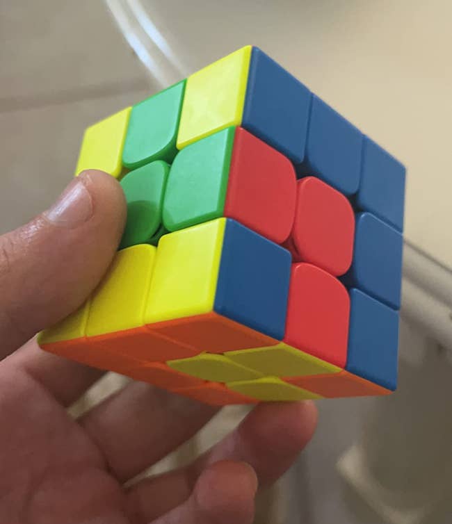 Hand holding a solved Rubik's Cube