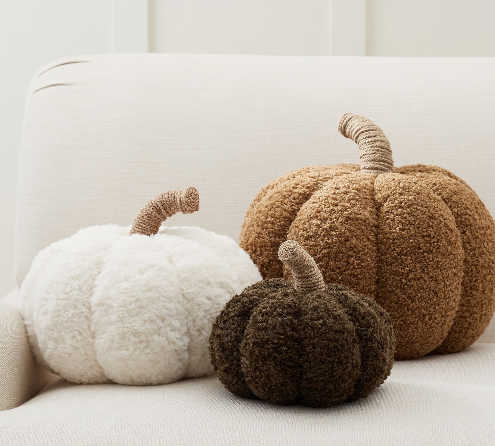 the three cozy pumpkin pillows in white, light brown, and dark brown