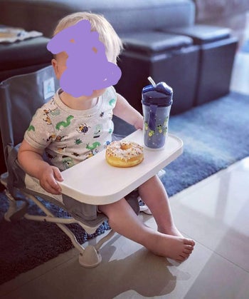 reviewer's photo of a child sitting in the booster chair 