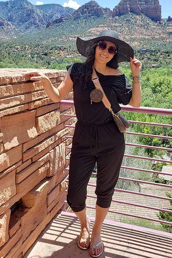 reviewer wearing the black jumpsuit while standing in front of mountain scenery