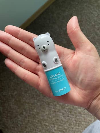 reviewer holding blue tube of hydrating eye stick with a polar bear top
