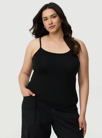 Person wearing a achromatic  camisole and escaped   pants, manus  successful  pocket, posing confidently