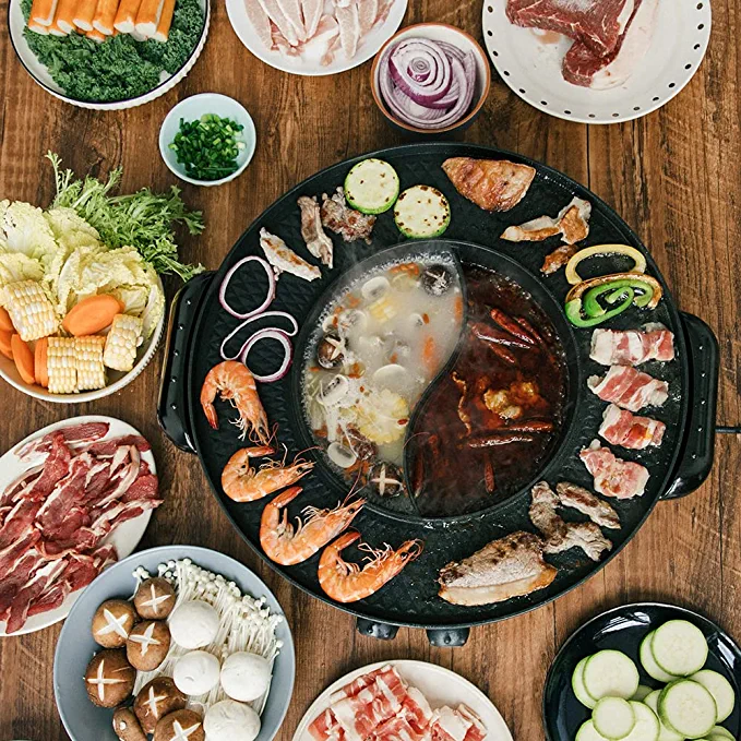 a hot pot and electric grill cooking shrimp, veggies, and assorted meats