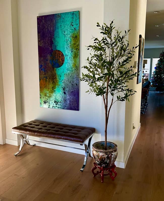 Reviewer's faux olive tree next to a bench and art piece