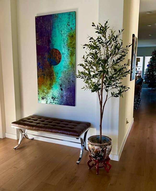 Reviewer's faux olive tree next to a bench and art piece