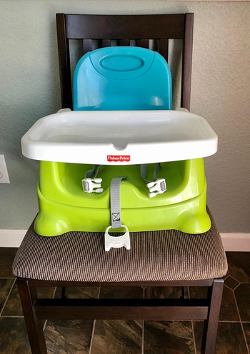 reviewer image of the fisher price booster seat on a dining chair