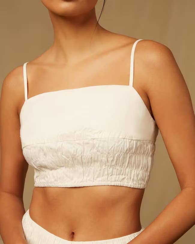 model in crop smocked top with spaghetti straps