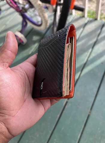 image of reviewer holding wallet in black filled with cards and cash