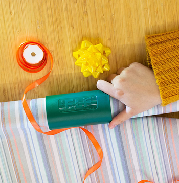 hand using the little elf to cut through a roll of wrapping paper