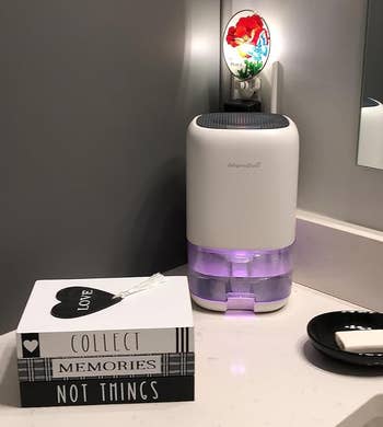 Small white dehumidifier with purple night-light glowing