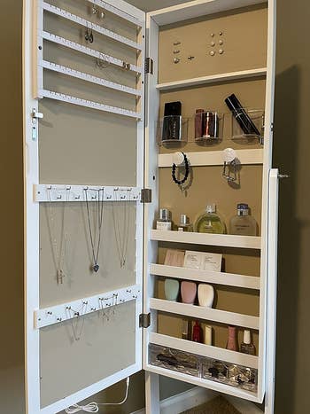 reviewer photo of their open mirror cabinet with jewelry and perfume bottles stored inside