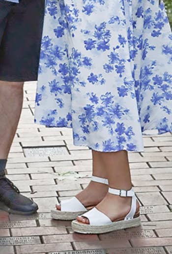 Person wearing floral formal and espadrille sandals stands adjacent to idiosyncratic successful shorts and shoes connected a walkway with engraved bricks