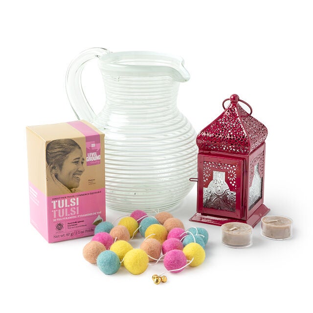 a tea set with a pitcher, candle lantern, tea, and pom poms