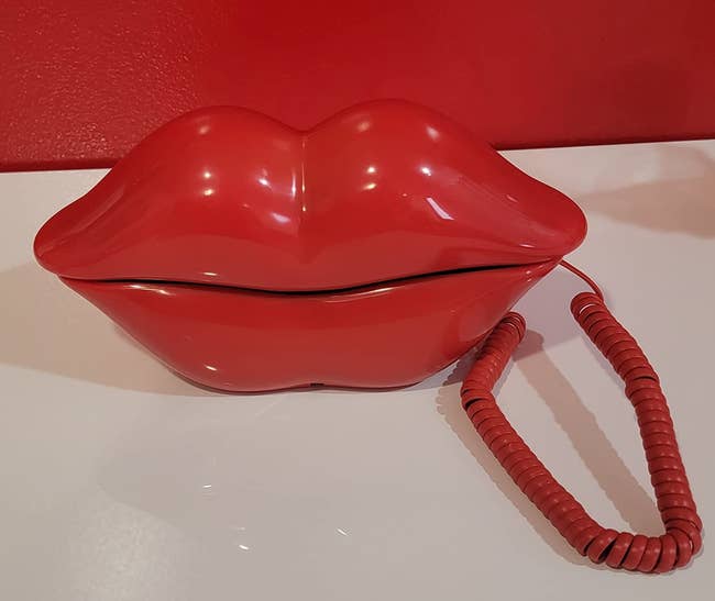 Unique red lip-shaped telephone on a white surface