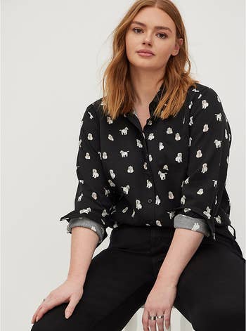 model in black button down printed with dogs that look like yellow labradoodles