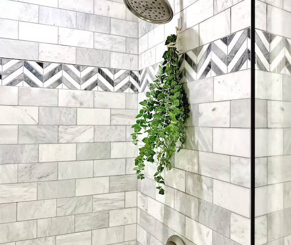 a eucalyptus bundle hanging from a shower wall underneath the shower head 