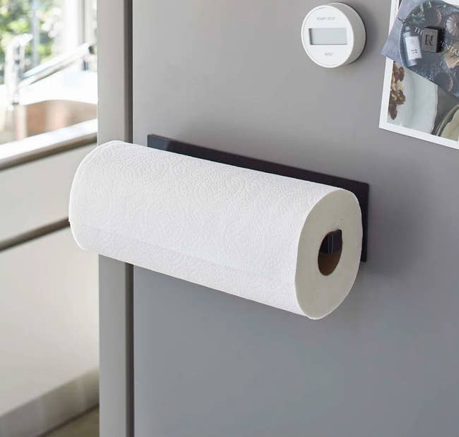Paper towel roll on a magnetic holder attached to a fridge