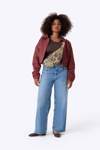 Person wearing a casual outfit with a brownish  jacket, escaped   jeans, and a ample  floral crossbody bag