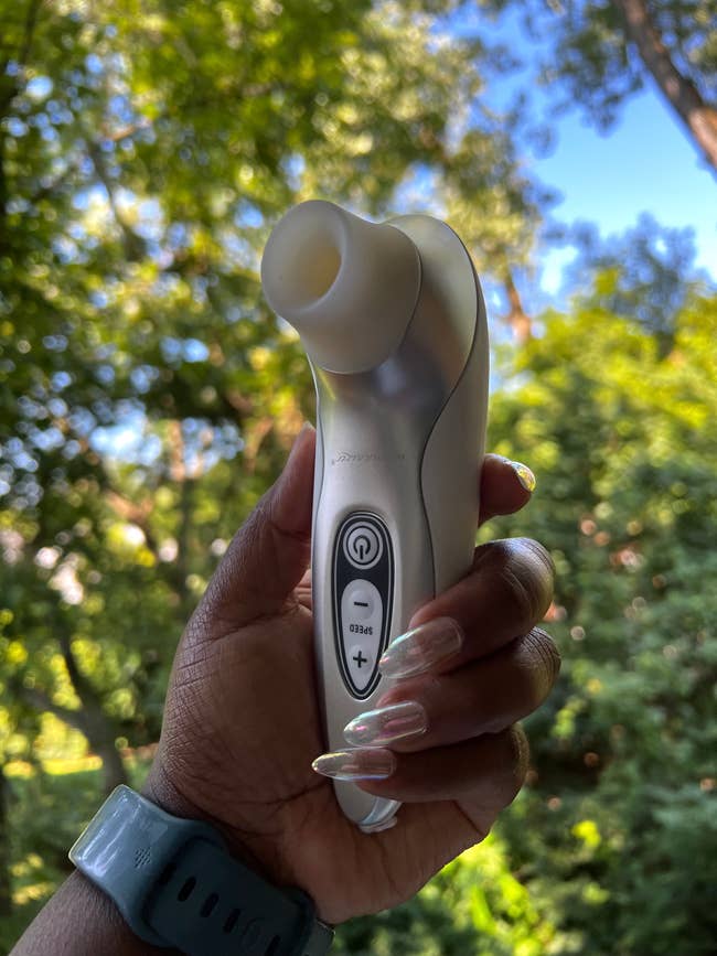 Hand holding white and silver suction vibrator
