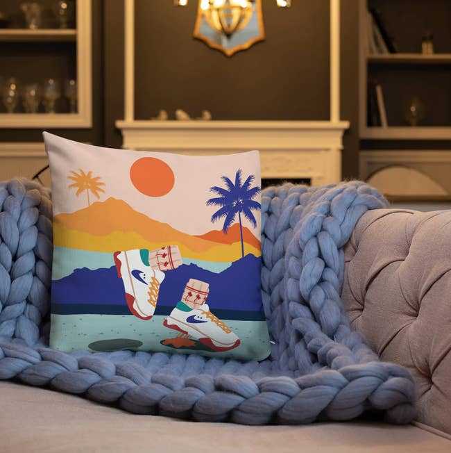 Decorative pillow with a beach and sneaker print on a chunky knit blanket on a couch. Perfect for home decor enthusiasts