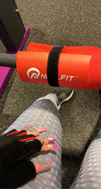 reviewer sits next to barbell with red pad