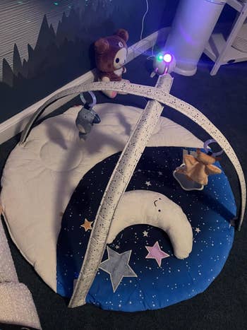 Baby play gym with a starry mat, plush moon, and hanging toys including a bear, elephant, and star, acceptable successful a cozy play area