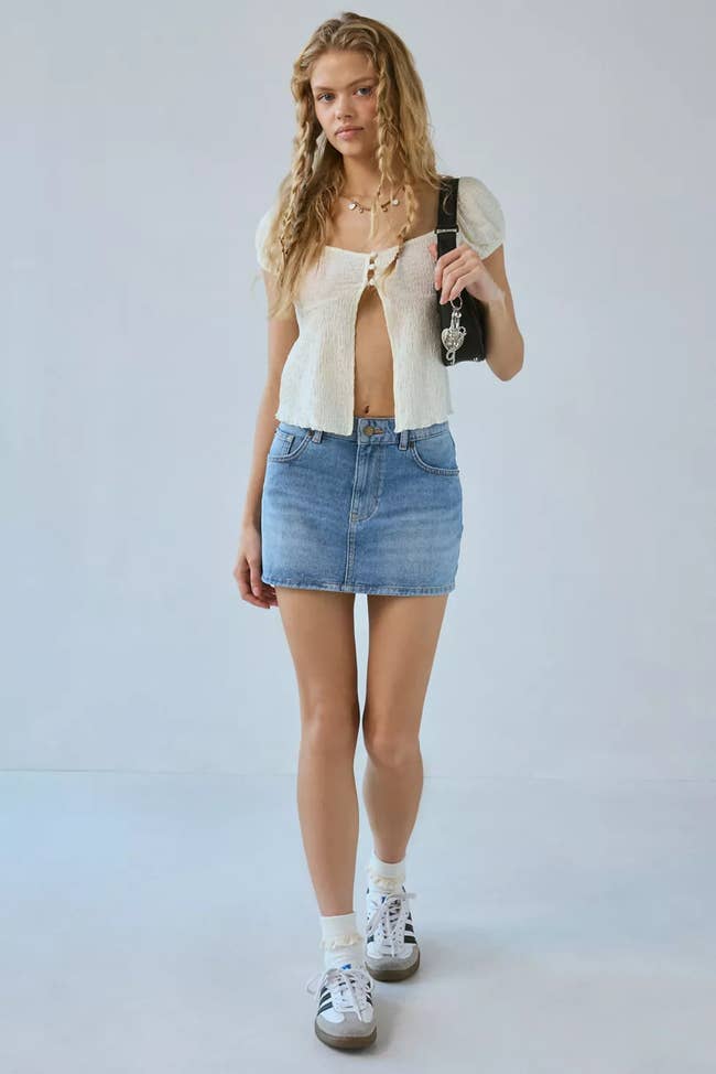 Person successful  a casual outfit with a short-sleeve top, denim skirt, and sneakers, carrying a enarthrosis  bag, cleanable   for a relaxed, trendy style