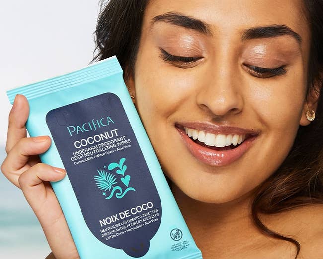 model smiling portion holding a battalion of Pacha coconut beverage deodorant wipes, advertised arsenic gentle and refreshing for on-the-go use