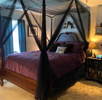 a reviewer photo of a four post bed with a black canopy installed 