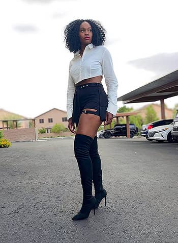 reviewer photo of them wearing black suede thigh-high stiletto boots with black shorts and a white top